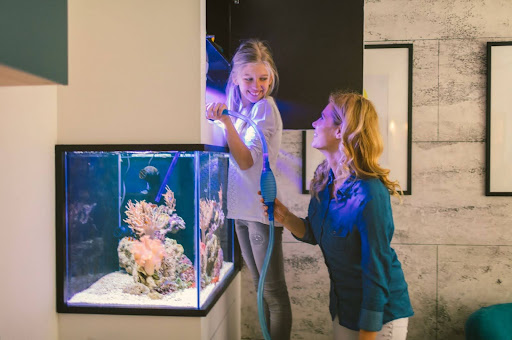 Mother and daughter cleaning acrylic sheet aquarium at home